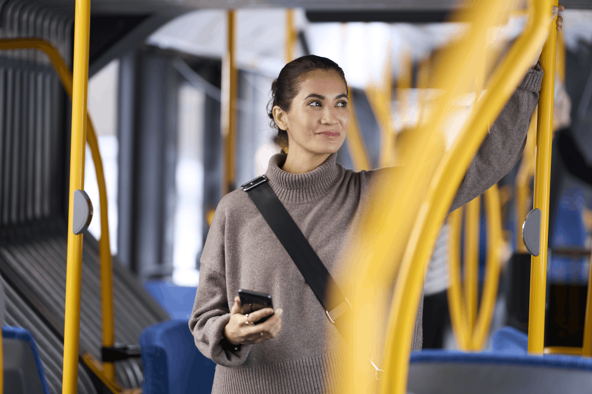 A woman in a bus holding a mobile device 