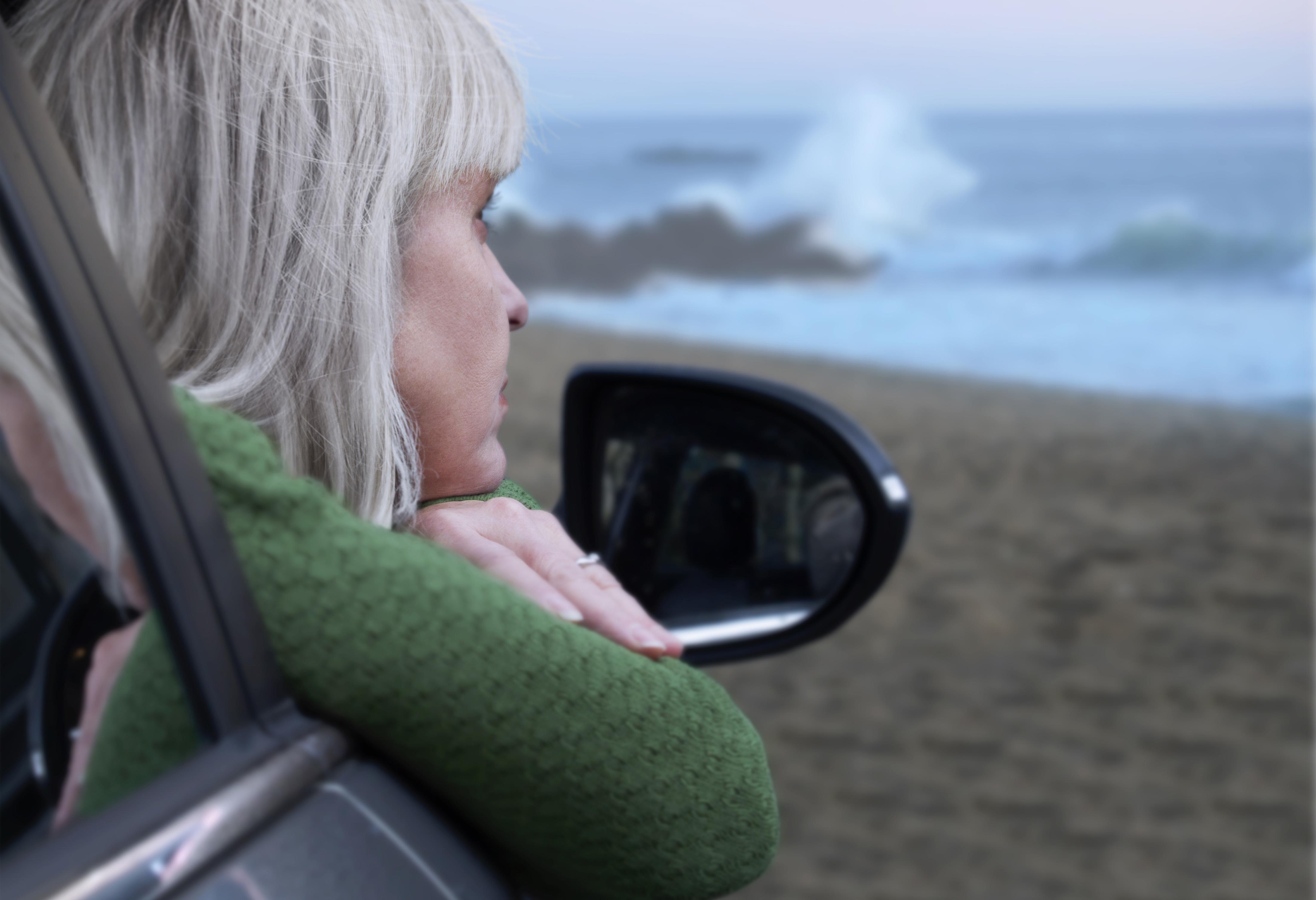 Woman at the beach looking pensative.