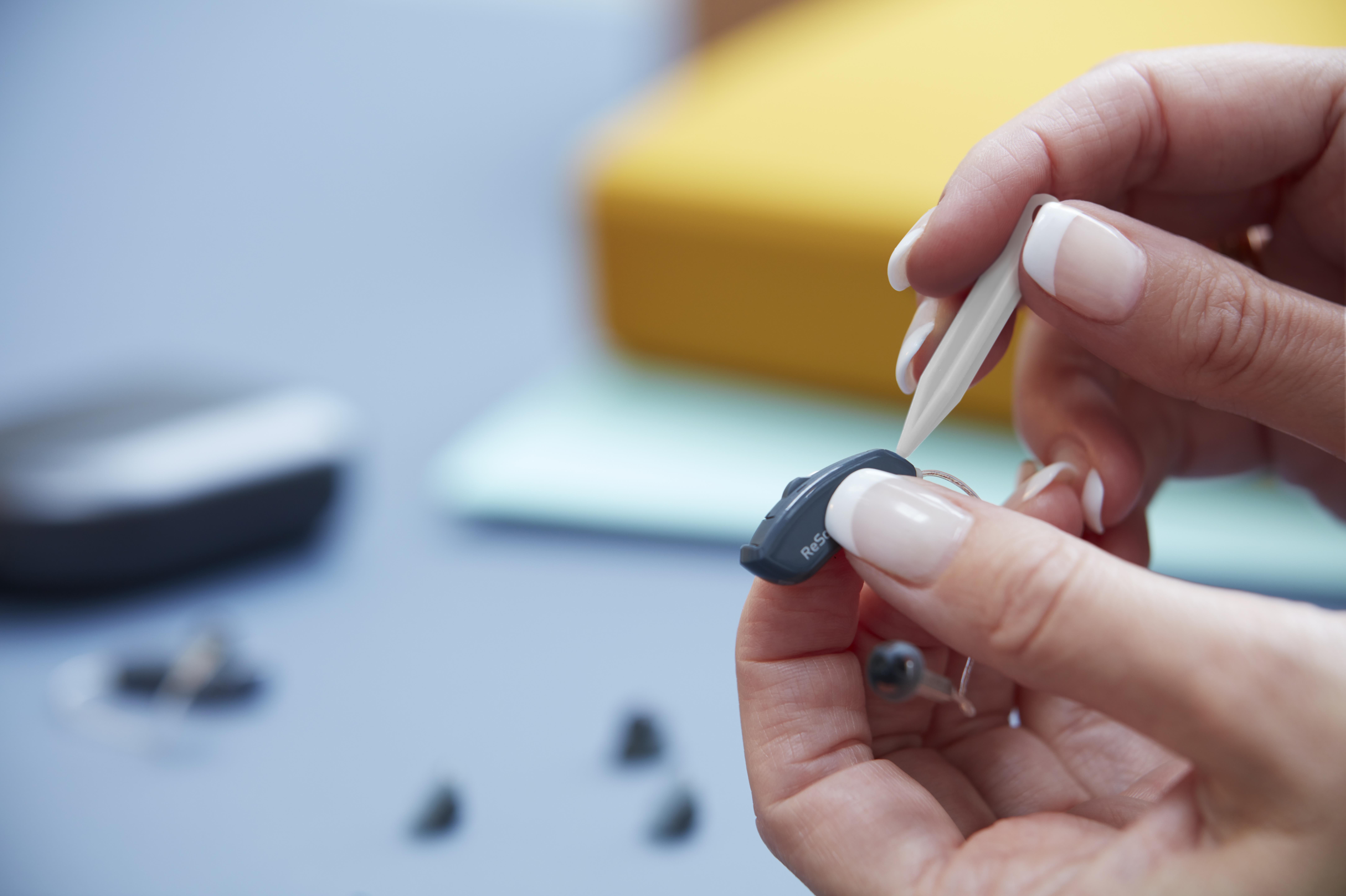 Hearing care professional fixing a hearing aid. 